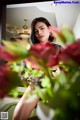 A woman sitting in front of a mirror with a vase of flowers.