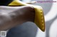 A close up of a person's hand holding a pair of yellow shoes.