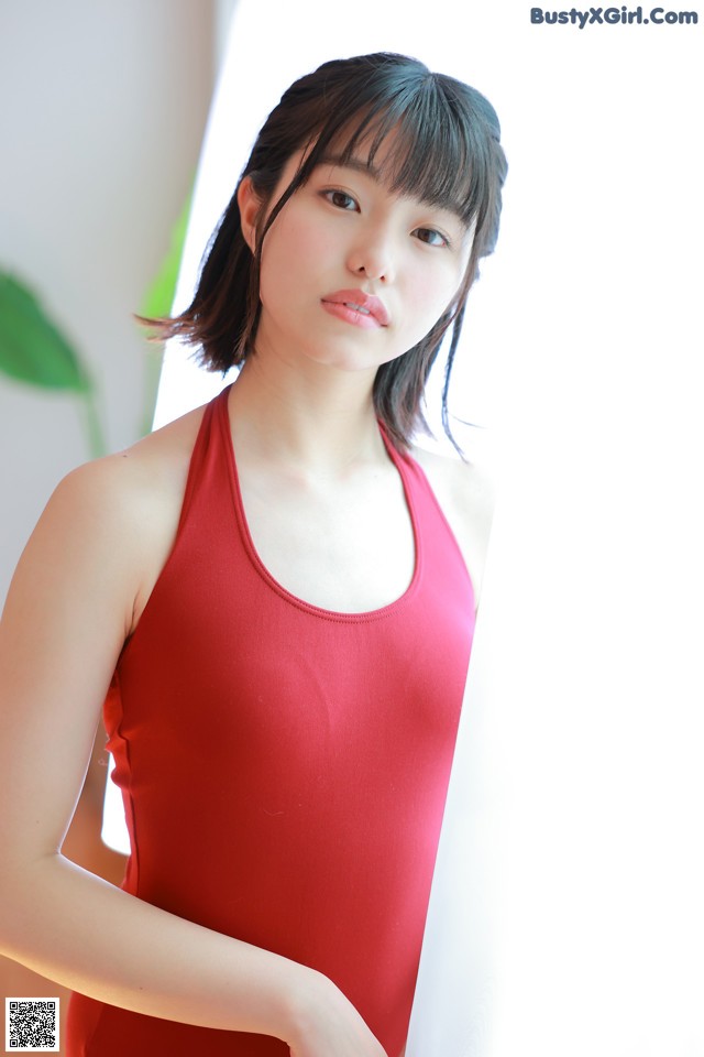 A woman in a red tank top posing for a picture.