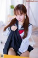 A young woman in a school uniform sitting on a chair.