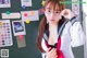 A woman wearing glasses standing in front of a blackboard.